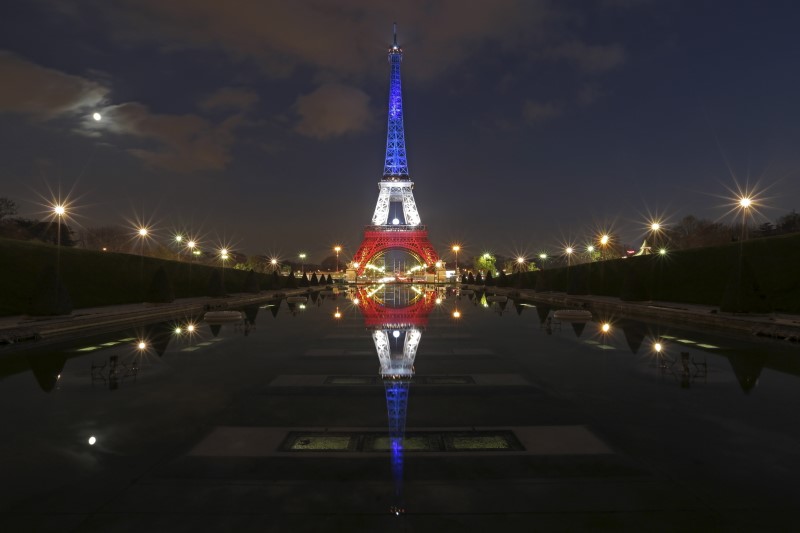 © Reuters. The Eiffel Tower lit with the blue, white and red colours of the French flag is reflected in the Trocadero fountains in Paris