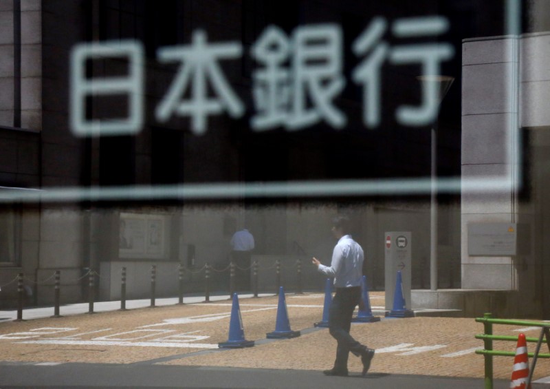 © Reuters. A man is reflected in a sign board of the Bank of Japan building in Tokyo