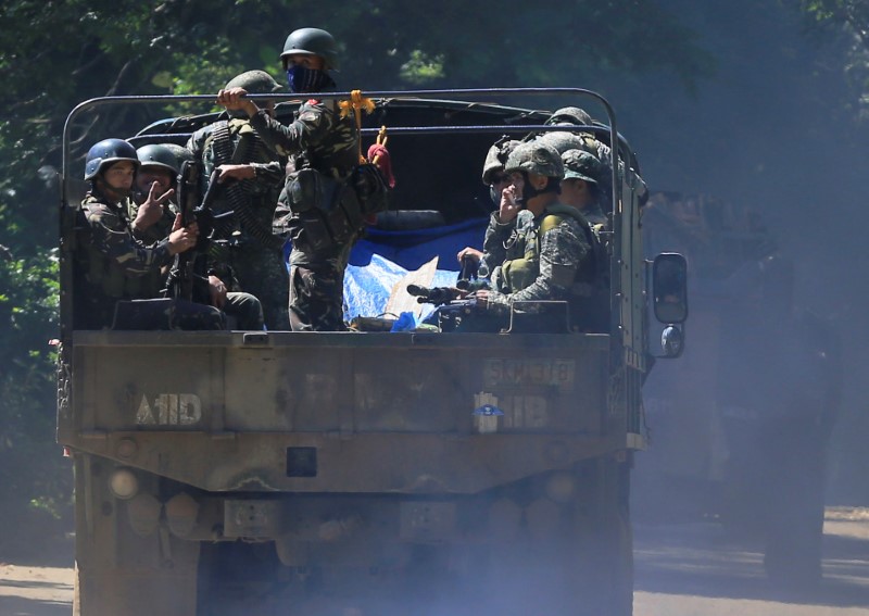 © Reuters. A government soldier flashes a 'Peace' sign while onboard a military truck with other soldiers as they continue their assault against insurgents from the Maute group, who have taken over large parts of Marawi City