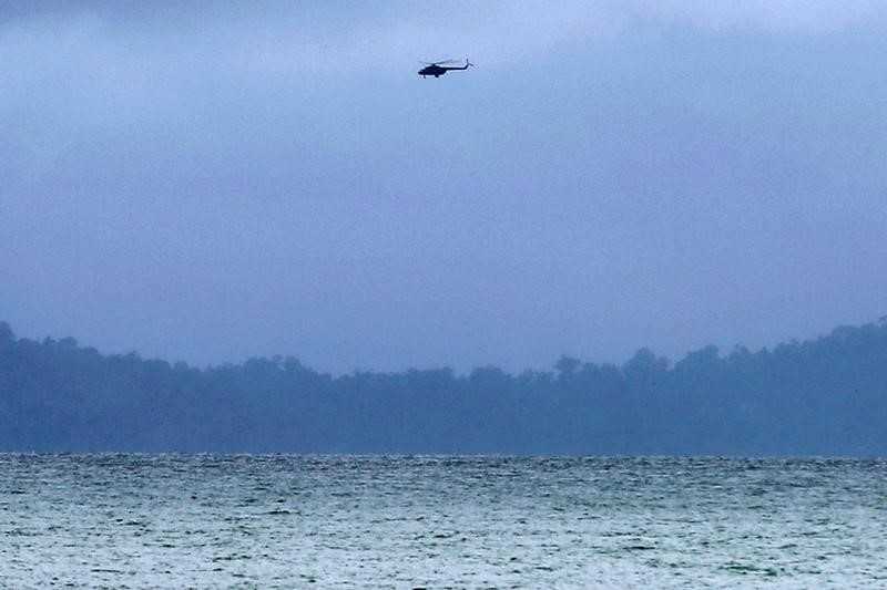 © Reuters. Rescue workers in an helicopter search for a crashed military plane outside Launglon township