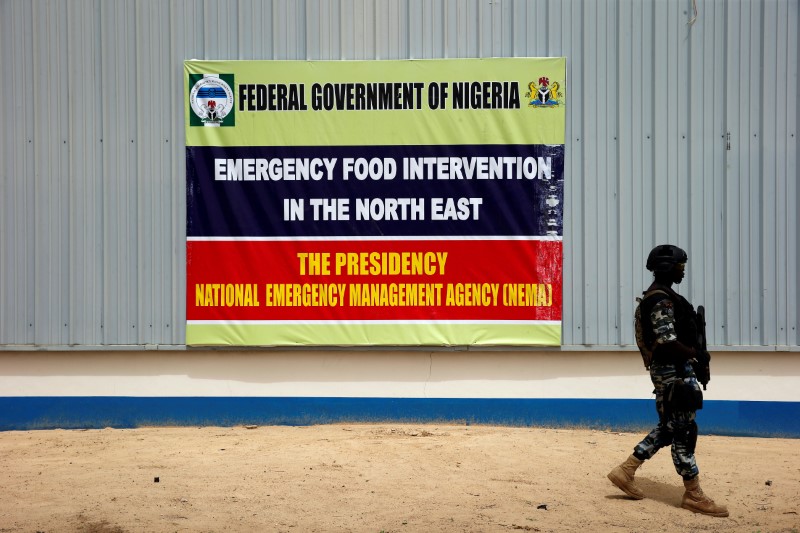 © Reuters. A soldier walks past a banner pasted on a warehouse where food and relief materials for the internal displaced persons are stored in Maiduguri.