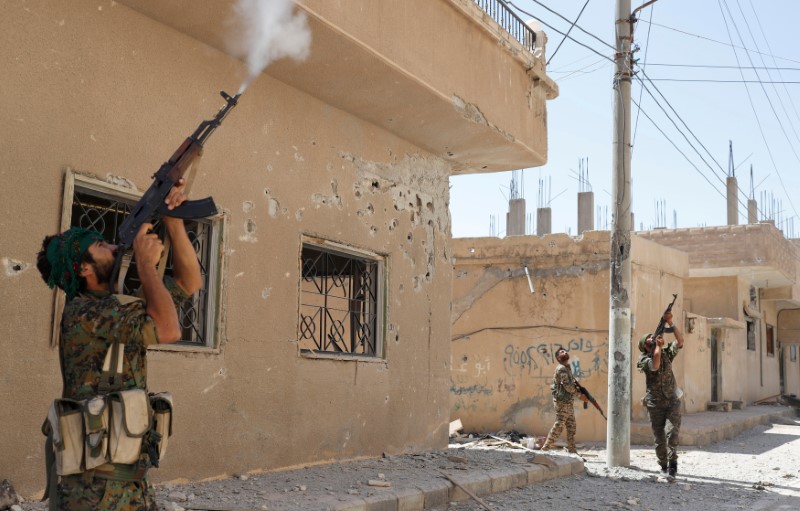 © Reuters. Kurdish fighters from the People's Protection Units (YPG) fires rifles at a drone operated by Islamic State militants in Raqqa