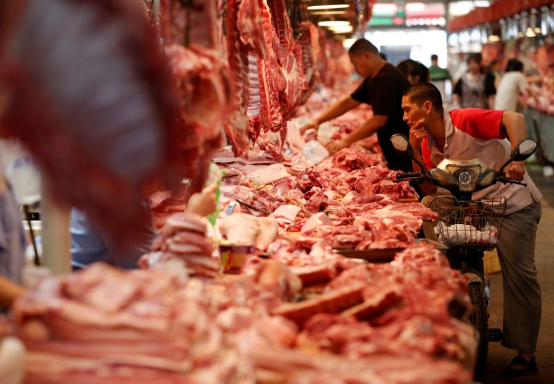 © Reuters. FILE PHOTO: A customer chooses meat at a meat market in Beijing