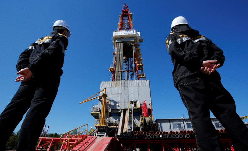 © Reuters. FILE PHOTO: Workers look at a drilling rig at an oil field outside Nefteyugansk