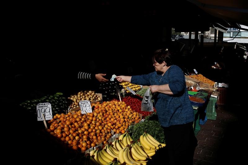 © Reuters. A woman pays for fruit and vegetables at a main food market in central Athens