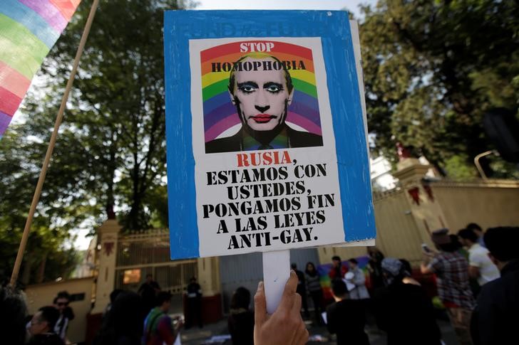 © Reuters. A member of the LGBT community, holds a placard wih the picture of Russia's President Vladimir Putin during a protest outside the Russian embassy, in Mexico City