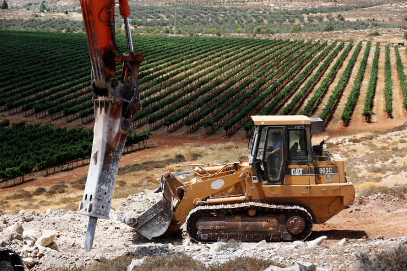 © Reuters. A man operates a bulldozer on a field as work begins on the construction of Amichai, a new settlement which will house some 300 Jewish settlers evicted in February from the illegal West Bank settlement of Amona, in the West Bank