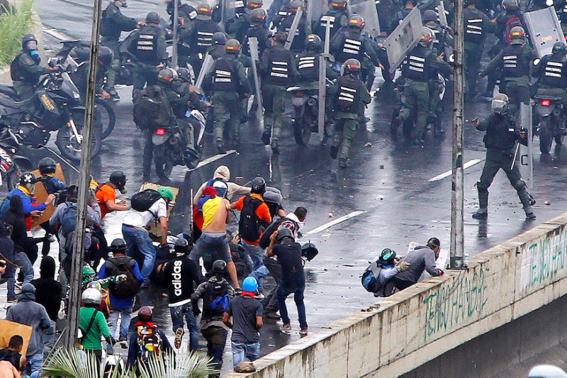 © Reuters. A member of the riot security forces points what appears to be a pistol towards a crowd of demonstrators during a rally against Venezuela’s President Nicolas Maduro’s government in Caracas,