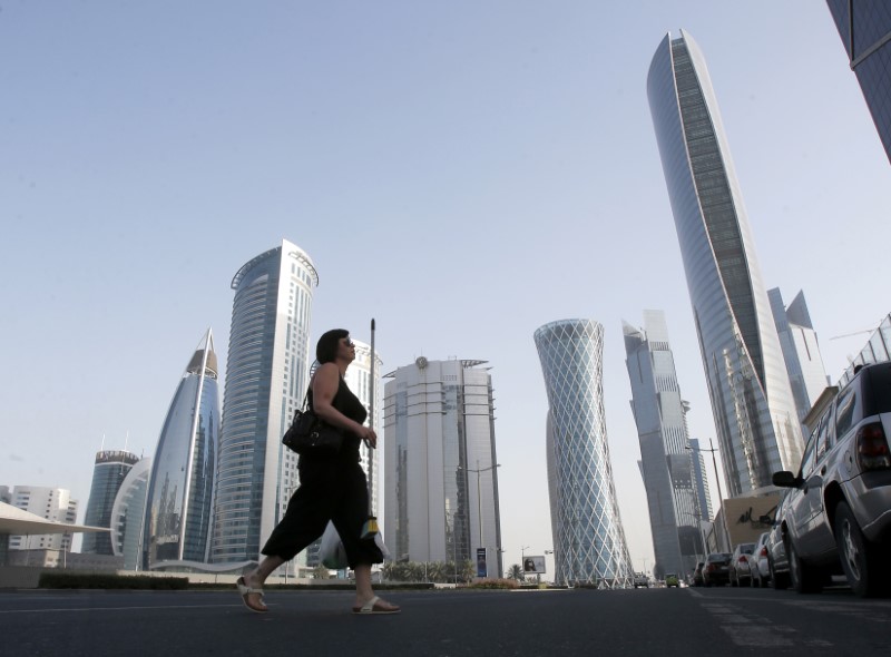 © Reuters. A woman crosses Al Wahda street hosting the Navigation Tower, headquarters of Qatargas, and Rasgas tower in Doha