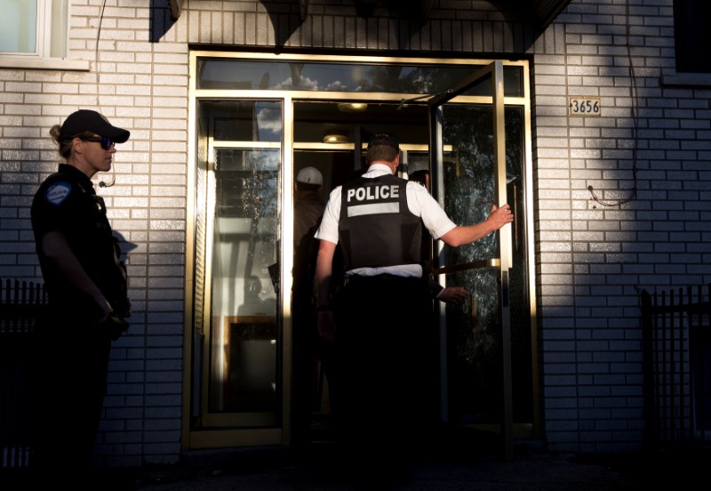 © Reuters. Police investigators walk into the residence of Amor Ftouhi in Montreal