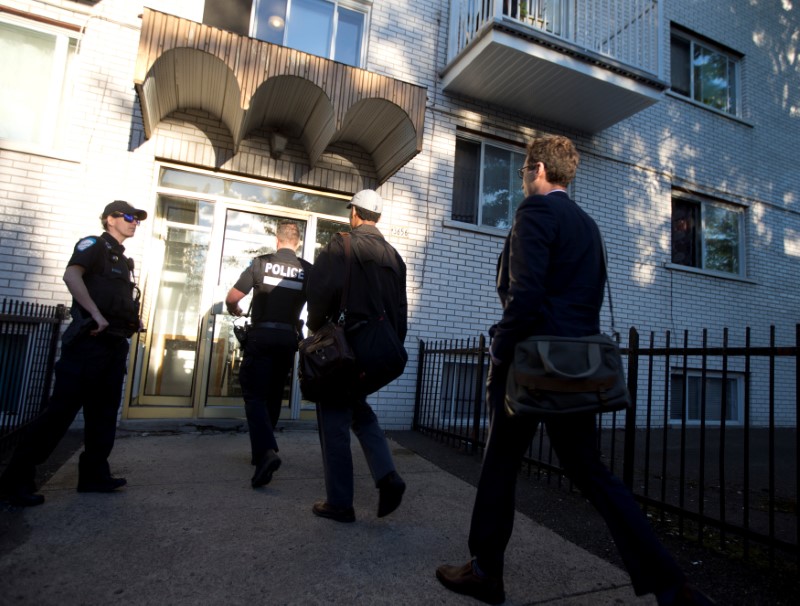 © Reuters. Police investigators walk into the residence of Amor Ftouhi in Montreal