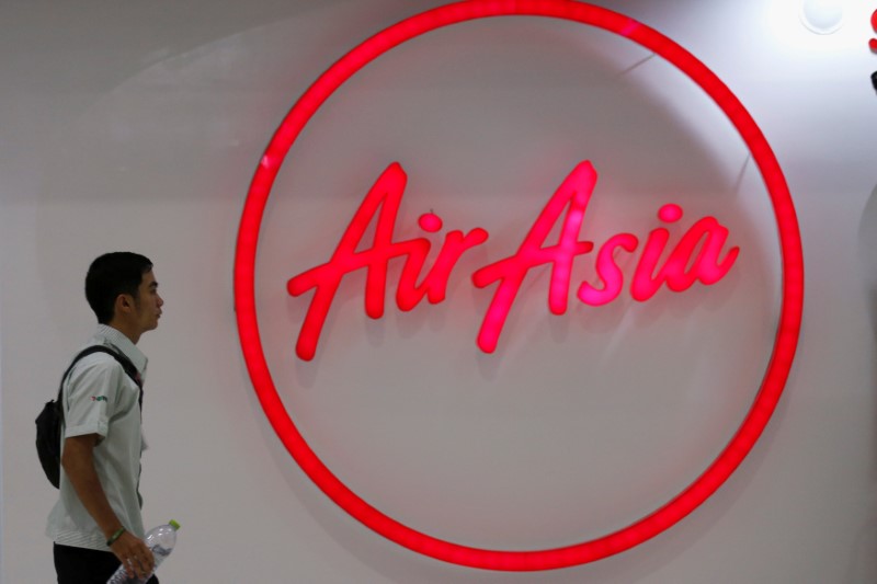 © Reuters. FILE PHOTO -  A man walks past the logo of AirAsia at Don Muang International Airport in Bangkok