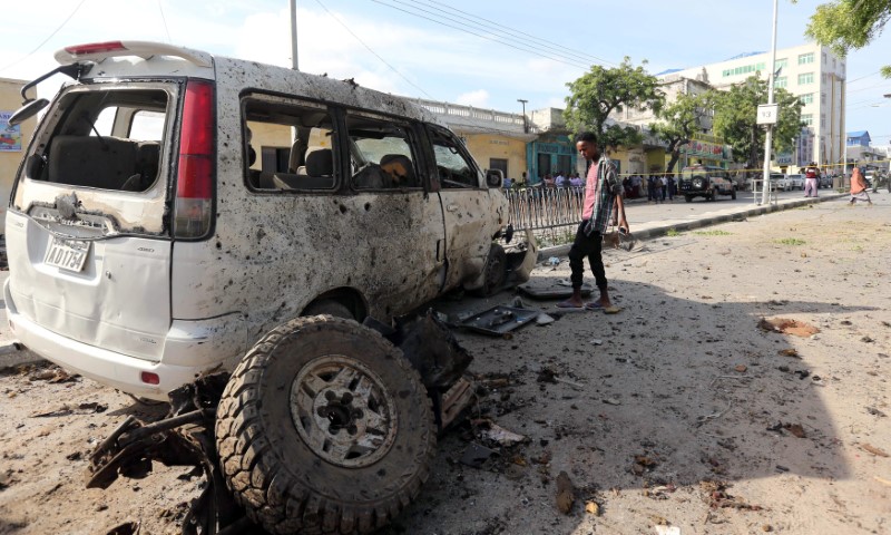 © Reuters. A boy looks at a wreckage of a car at the scene of an explosion near Waberi police station station in Mogadishu