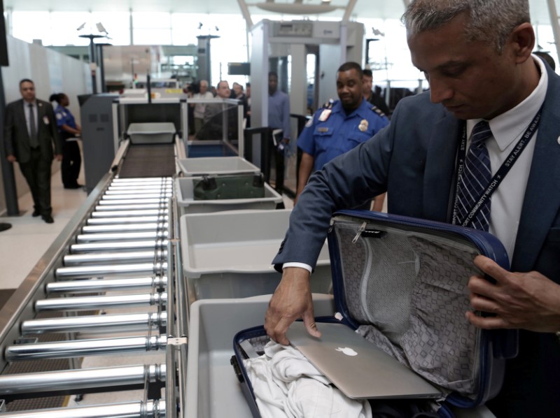 © Reuters. FILE PHOTO: A TSA official removes a laptop from a bag for scanning using the Transport Security Administration's new Automated Screening Lane technology at Terminal 4 of JFK airport in New York City