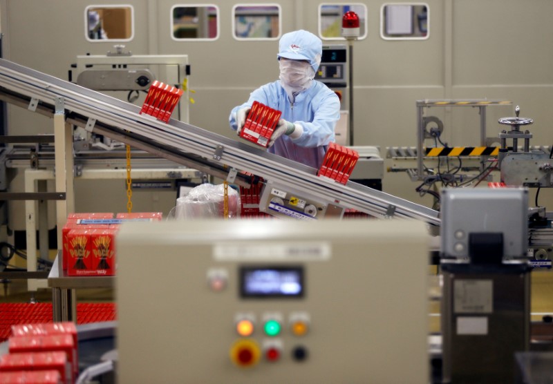 © Reuters. FILE PHOTO: Employee of Ezaki Glico works on a Pocky production line at the company's Kitamoto factory in Kitamoto