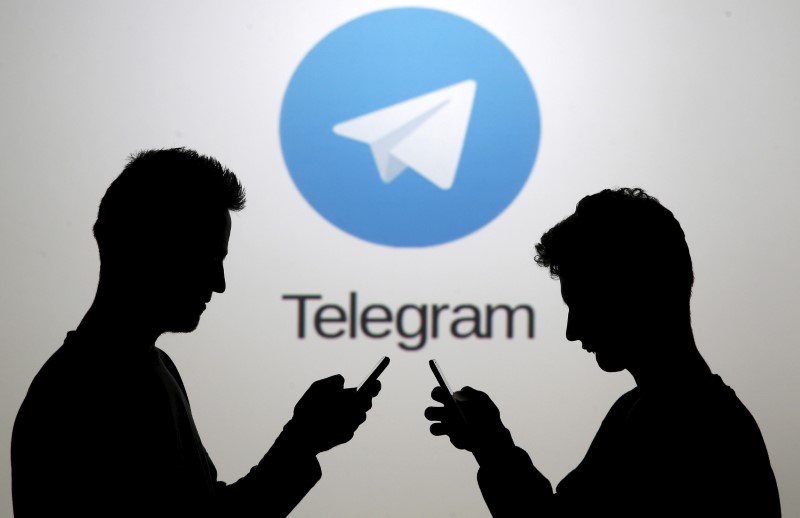 © Reuters. Two men pose with smartphones in front of a screen showing the Telegram logo in this picture illustration taken in Zenica