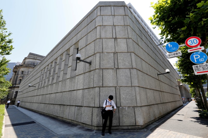 © Reuters. A man looks at a mobile phone in front of the Bank of Japan building in Tokyo