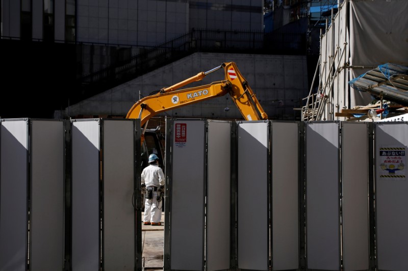 © Reuters. FILE PHOTO: A worker is pictured next to heavy machinery at a construction site in Tokyo's business district