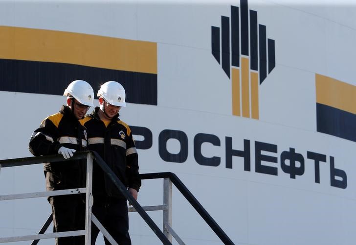 © Reuters. FILE PHOTO: Workers stand next to a logo of Russia's Rosneft oil company at central processing facility of Rosneft-owned Priobskoye oil field outside Nefteyugansk