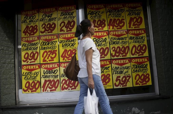 © Reuters. Consumidora passa por cartazes com preços de produtos do lado de fora de um mercado no Rio de Janeiro