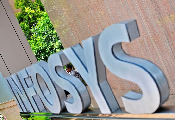 © Reuters. FILE PHOTO: An employee is seen behind an Infosys logo at the company's campus in Bangalore