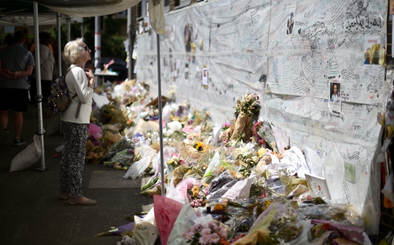 © Reuters. A woman looks at flowers, tributes and messages left for the victims of the fire at the Grenfell apartment tower in North Kensington