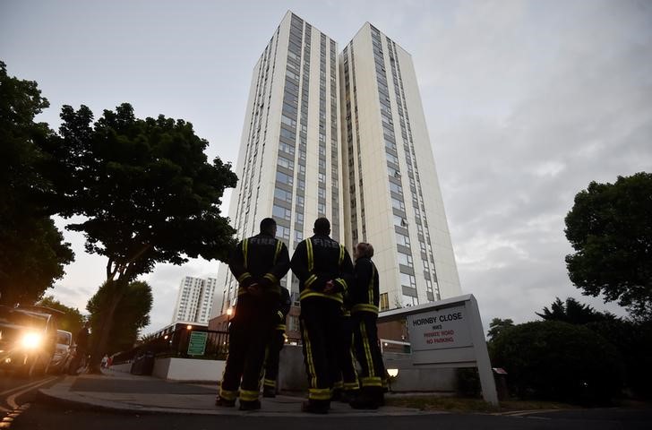 © Reuters. Firefighters stand outside the Burnham Tower residential block, as residents were evacuated as a precautionary measure following concerns over the type of cladding used on the outside of the building on the Chalcots Estate in north London