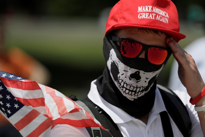 © Reuters. A masked demonstrator in a Donald Trump "Make America Great Again" hat wipes his brow as self proclaimed "White Nationalists", white supremacists and members of the "Alt-Right" gather for what they called a "Freedom of Speech" rally at the Lincoln Memorial