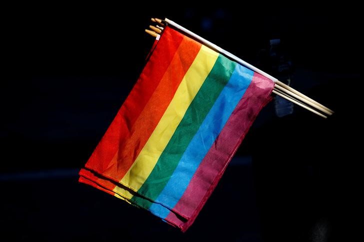 © Reuters. A man sells rainbow flags near The Stonewall Inn, on the eve of the LGBT Pride March, in the Greenwich Village section of New York