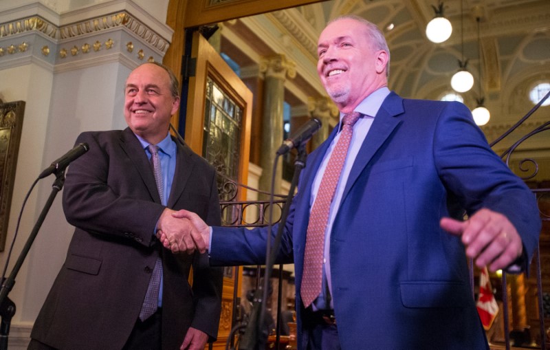 © Reuters. BC Green leader Andrew Weaver and BC New Democrat leader John Horgan shake hands outside the gates of the British Columbia legislature building in Victoria