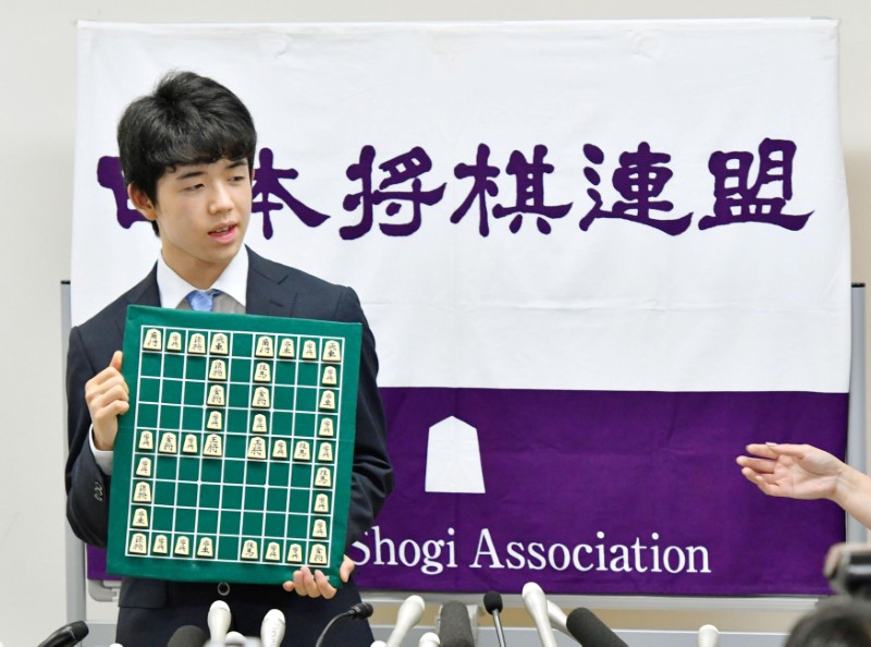 © Reuters. Japan's youngest professional shogi player Sota Fujii holds a shogi board with the number 29 portrayed with shogi pieces in Tokyo