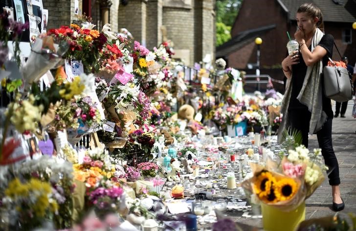 © Reuters. Mulher observa flores e mensagens deixadas para vítimas de incêndio em prédio residencial em Londres