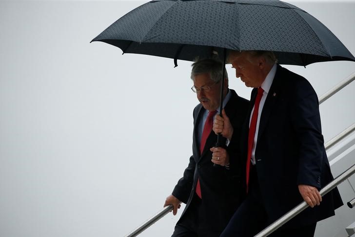 © Reuters. Trump holds an umbrella over Branstad as they arrive together aboard Air Force One at Eastern Iowa Airport in Cedar Rapids, Iowa