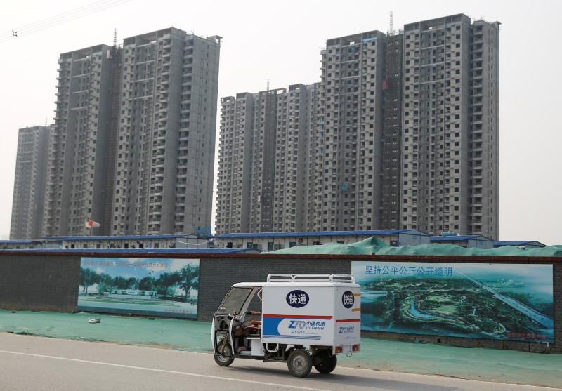 © Reuters. A delivery vehicle of the logistical company ZTO drives past a construction site of residential highrises in Beijing