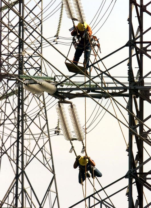 © Reuters. Funcionários da Eletropaulo trabalham em torre de energia elétrica