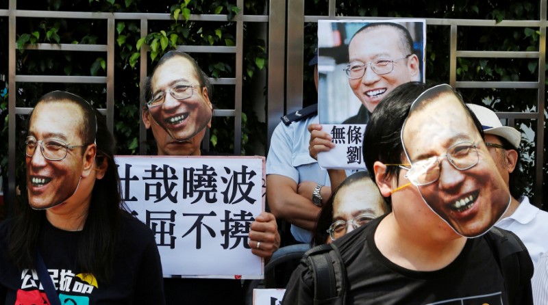 © Reuters. Protesters wearing masks of Chinese Nobel rights activist Liu Xiaobo stand outside China's Liaison Office in Hong Kong, China