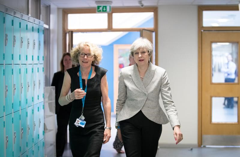 © Reuters. Britain's Prime Minister Theresa May walks with head teacher Dr Helen Holman after sitting in on a session for teachers receiving training in mental health support at Orchard School, in Bristol