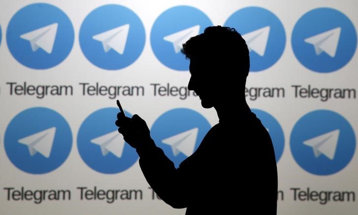 © Reuters. Мужчина с телефоном на фоне логотипов мессенджера Telegram в Зенице