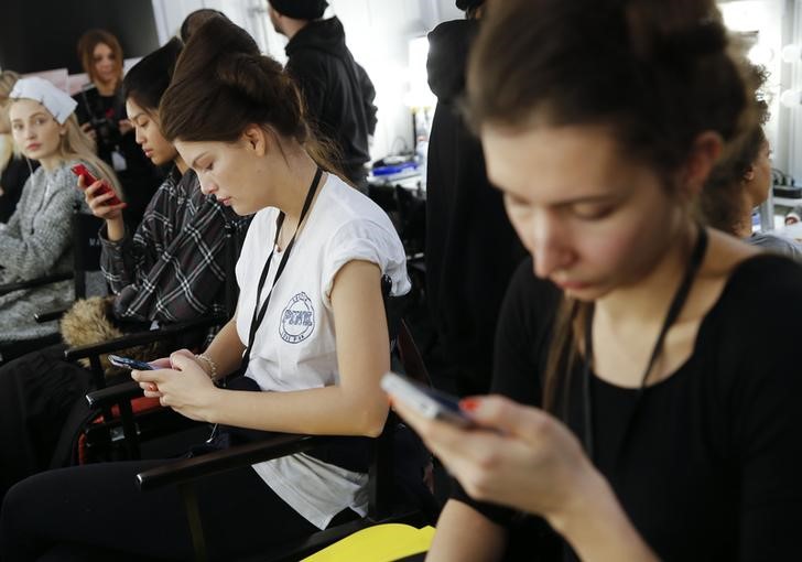 © Reuters. Models use their mobile phones backstage at the Berlin Fashion Week