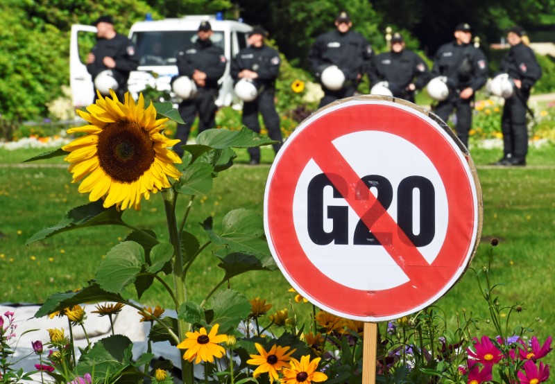 © Reuters. A G20 protest sign is seen in front of a row of police men during a demonstration against the ban of Hamburg's authorities of a G20 protestors camp in the Stadtpark park in Hamburg