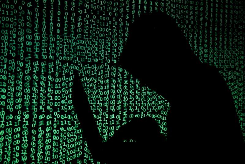 © Reuters. Hooded man holds laptop computer as cyber code is projected on him in this illustration picture