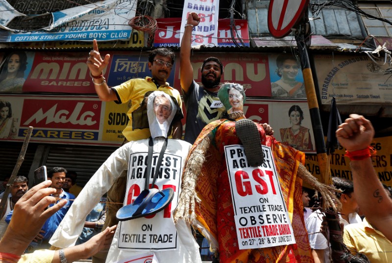 © Reuters. Cloth merchants and workers shout slogans before burning the effigies depicting India's Finance Minister Arun Jaitley and Textiles Minister Smriti Irani during a protest against implementation of Goods and Services Tax (GST) on textiles, in Kolkata