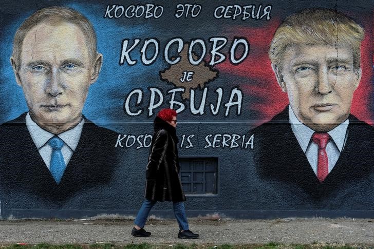 © Reuters. Mulher caminha em frente a mural que retrata o presidente russo Vladimir Putin e norte-americano Donald Trump na Sérvia