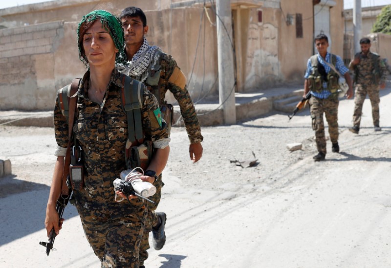 © Reuters. Sheen Ibrahim, Kurdish fighter from the People's Protection Units (YPG) walks together with other  YPG fighters in Raqqa