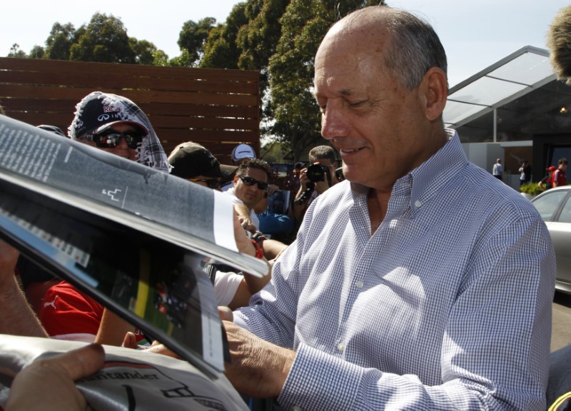 © Reuters. Chairman and CEO of McLaren Formula One team Dennis signs autographs at the first practice session of the Australian F1 Grand Prix in Melbourne