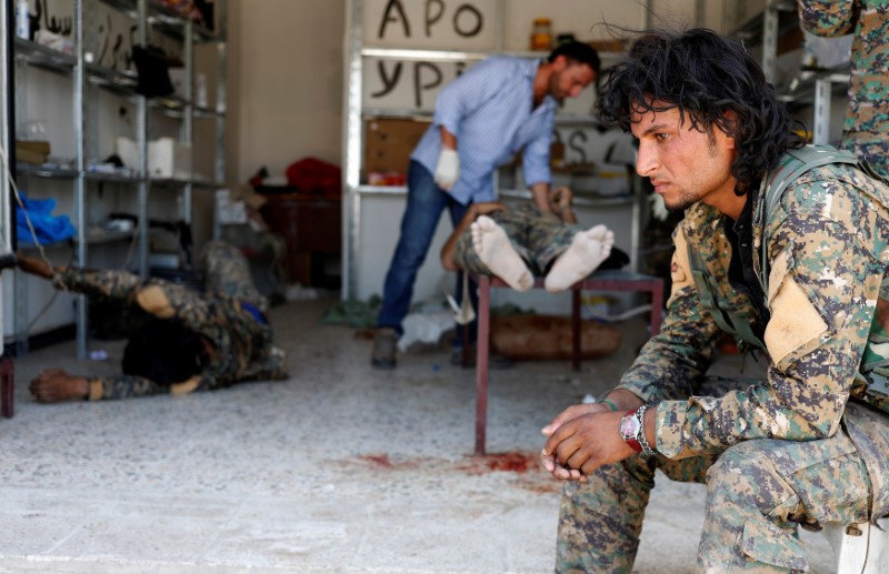 © Reuters. A Syrian Democratic Forces (SDF) fighter sit as medics treat his comrades injured by sniper fired by Islamic State militants in a field hospital in Raqqa