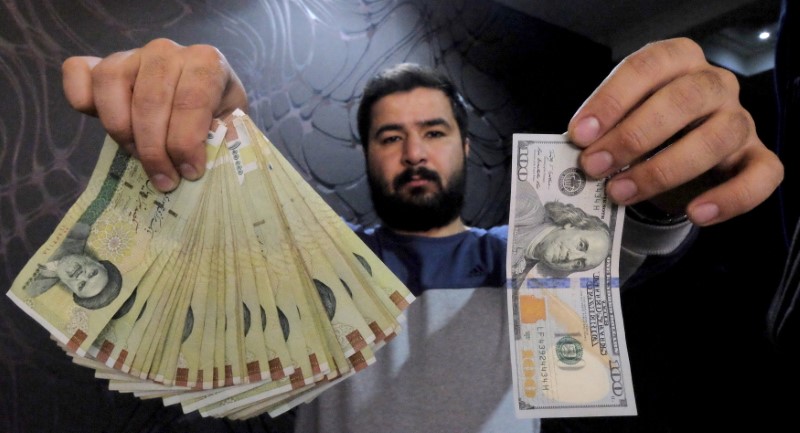 © Reuters. Money changer poses for the camera with a U.S dollar and the amount being given when converting it into Iranian rials, at a currency exchange shop in Tehran's business district, Iran