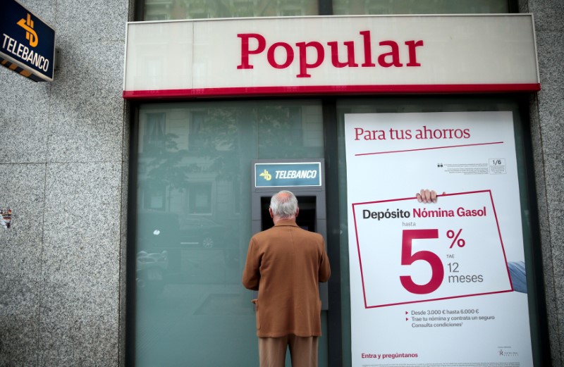 © Reuters. FILE PHOTO: A man uses a cash dispenser at a Banco Popular branch in Madrid