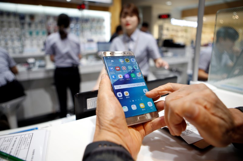 © Reuters. FILE PHOTO: A customer uses his Samsung Electronics' Galaxy Note 7 as he waits for exchange at company's headquarters in Seoul