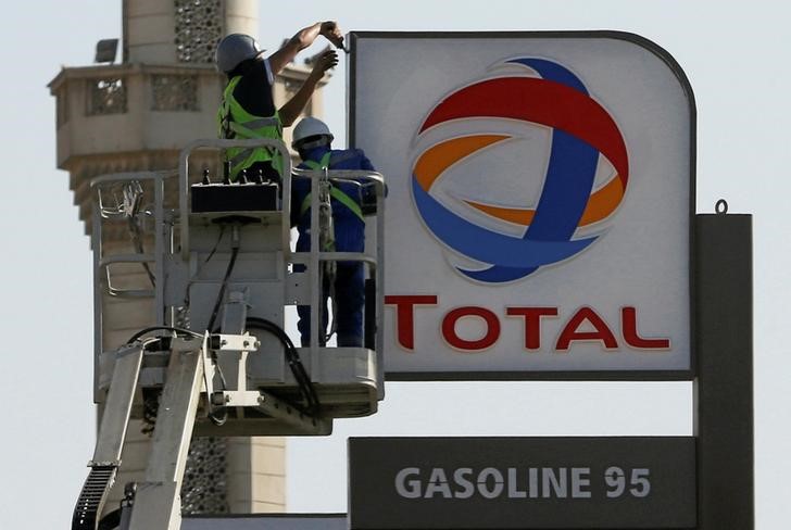 © Reuters. Workers fix a sign for oil giant Total at a petrol station in Cairo